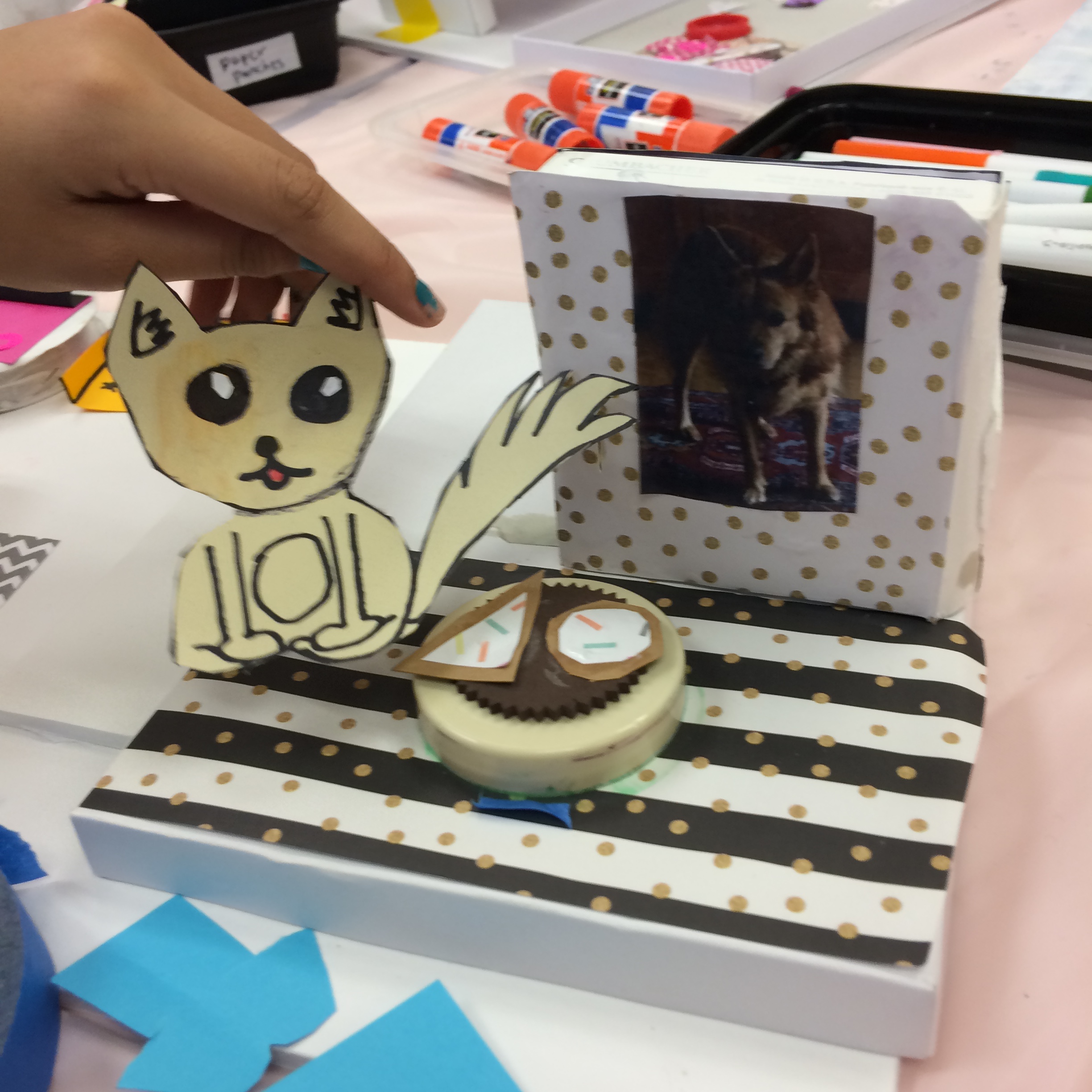 Cartoon of dog drawn by student next to a photo of dog. Both are placed near a round table with paper "food."
